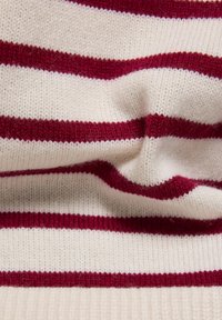 Gestricktes Kleidungsstück mit abwechselnden cremefarbenen und burgunderroten Streifen, das eine weiche Textur und eine lockere, fallende Form zeigt.