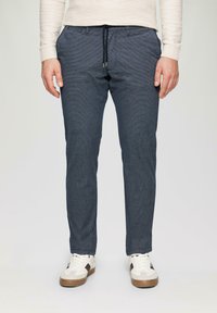 Marineblaue karierte Hose mit elastischem Bund, gerader Passform und Seitentaschen, kombiniert mit beigen Low-Top-Sneakern mit braunen Akzenten.