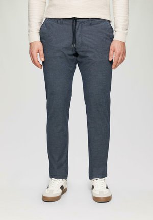 Marineblaue karierte Hose mit elastischem Bund, gerader Passform und Seitentaschen, kombiniert mit beigen Low-Top-Sneakern mit braunen Akzenten.