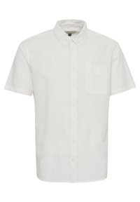 Camisa de lino blanca de manga corta con cuello abotonado, un bolsillo en el pecho y un corte relajado. Textura suave, material ligero.