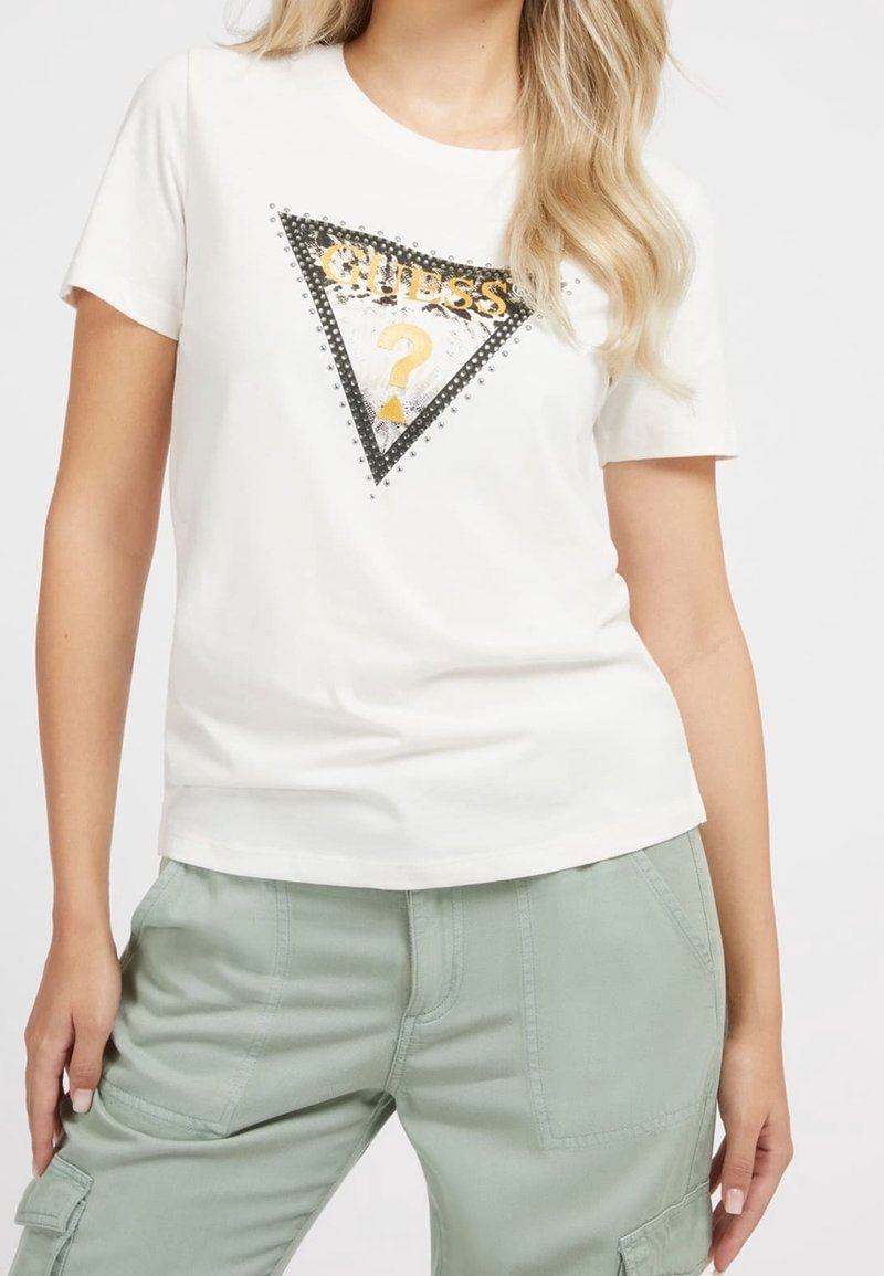 Camiseta de algodón blanca de manga corta, con un gráfico triangular en negro y plateado que presenta el texto "GUESS" y un signo de interrogación en dorado.