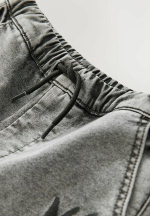 Grijze denim shorts hebben een elastische tailleband met een trekkoord, en tonen een vervaagde structuur en een minimalistisch ontwerp.