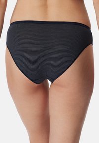 Slip bikini blu scuro con strisce orizzontali bianche, dotato di vita media e tessuto morbido e elastico per il comfort.