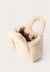 Kremfarget faux fur håndveske med myk tekstur, rektangulær form og doble topphåndtak. Inkluderer en glidelåslomme inni og lærdetaljer.