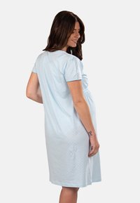 Camicia da notte in cotone azzurro chiaro con maniche a sbuffo corte, motivo a pois e delicata arricciatura elastica in vita. Lunghezza fino al polpaccio.