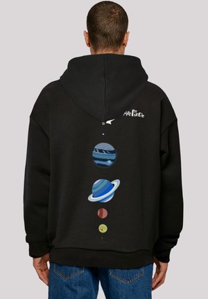 Sort hættepulli med et grafisk motiv af planeter i blå, grøn og rød, arrangeret lodret på ryggen, med en lille tekst nær toppen.