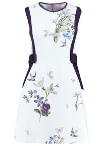 Robe blanche sans manches avec des panneaux latéraux bleu marine, imprimé floral et oiseaux, et deux nœuds bleus marine à la taille, dotée d'un col rond et d'une fermeture éclair au dos.