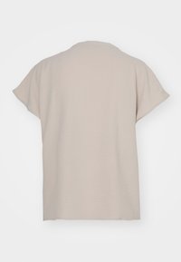 Top corto a maniche corte color beige chiaro con vestibilità comoda, scollatura tonda e texture liscia; nessun motivo o accentuazione visibile.