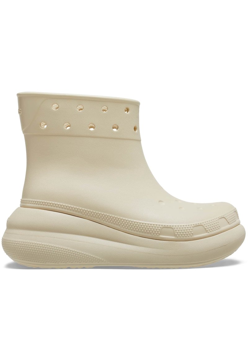 Bottine beige en caoutchouc avec des trous de ventilation circulaires, une semelle extérieure texturée et un bout arrondi. Dispose d'une semelle plateforme rembourrée.