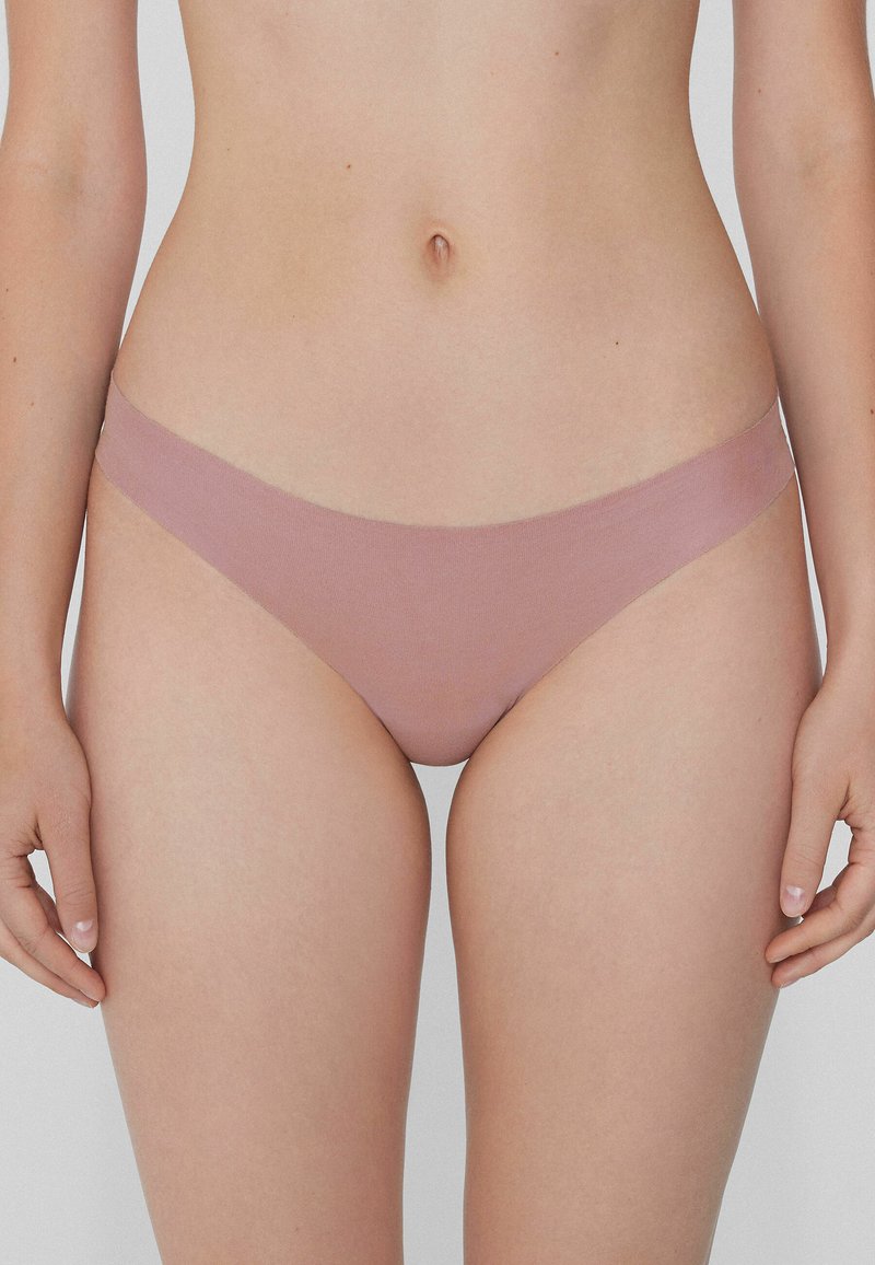 Růžový hladký tanga s minimalistickým designem a jemným pasem. Disponuje nízkým střihem.