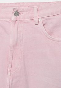 Nahaufnahme des Taillenbunds einer hellrosa Jeans aus Denim mit silberner Knopfleiste, Gürtelschlaufe und Details der Vorder taschennaht.