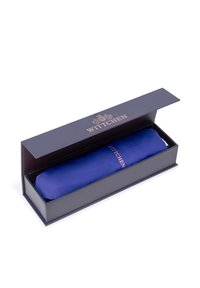 Ombrello blu confezionato in una scatola blu scura con accenti dorati. L'ombrello è avvolto in una copertura di tessuto che mostra il logo "Wittchen".