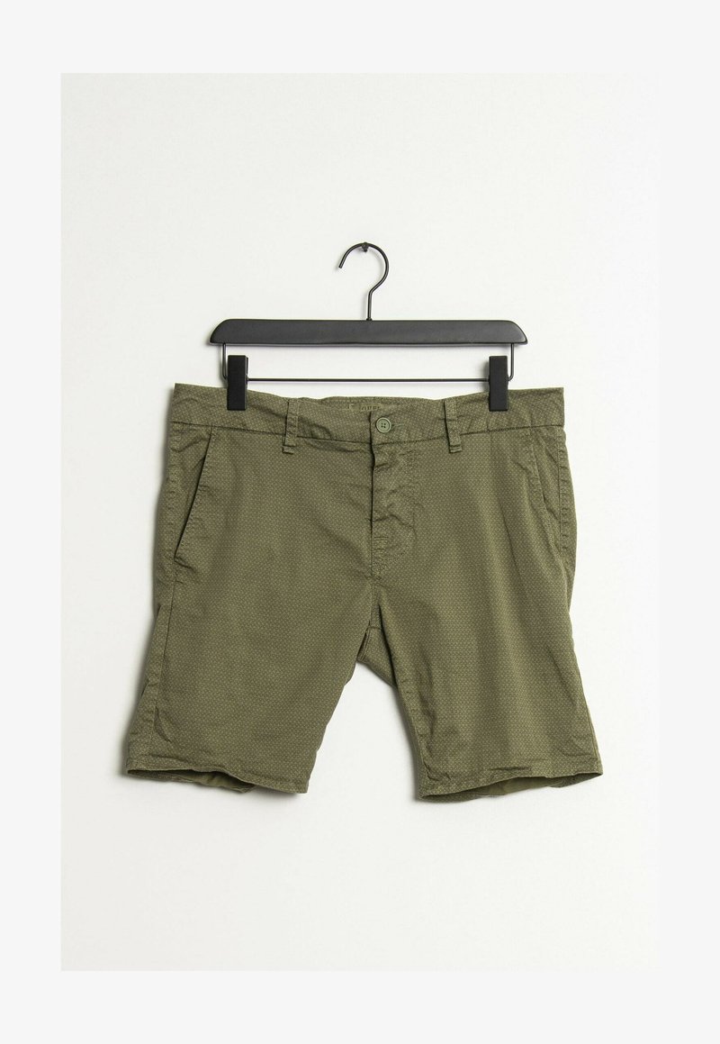 Shorts pour hommes à motif vert suspendus sur un cintre noir sur un fond blanc.