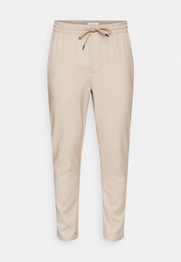 Beige sweatpants gjorda av mjukt tyg, med ett elastiskt midjeband och dragsko, sidofickor och avsmalnande ben.