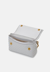 Bolso de mano tejido en blanco con una correa de cadena dorada, que cuenta con un cierre de solapa y bolsillos interiores, destacado por botones de presión dorados.