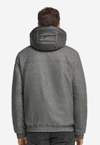 Grau Jacke aus einem strukturierten wollähnlichen Material, ausgestattet mit einer hüftlangen, grauen Kapuze und elastischen Bündchen. Der Saum ist ebenfalls elastisch für eine enge Passform.