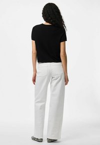 Mustat lyhyt hihaiset crop-topit yhdistettynä valkoisiin leveälahkeisiin farkkuihin. Farkuissa on takataskut ja siisti viimeistely. Kengissä on seepra-kuvio.