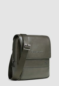 Borsa a spalla in pelle verde oliva con chiusura a patta, tracolla regolabile, logo impresso e tasca con zip. Texture liscia con linee pulite.