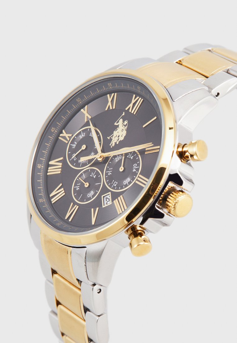 Reloj cronógrafo con esfera negra, números romanos dorados, pulsera de acero inoxidable en oro y plata, y tres subesferas con visualización de fecha.