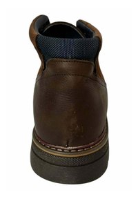 Botín de piel marrón con un cuello de tela azul marino, forma redonda, suela de goma y costuras en contraste a lo largo de la base.