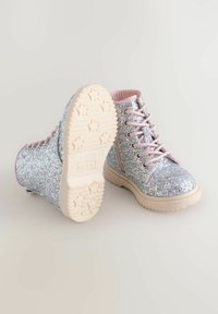 Bottines argentées scintillantes avec des lacets roses, une surface texturée, un bout arrondi et une semelle épaisse crème présentant un motif d'étoiles.