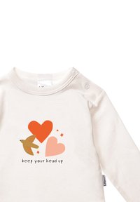 Helle beigen Langarmshirt mit einem Grafiken eines Vogels, zwei Herzen in Orange und Pink sowie dem Text "Halte den Kopf hoch" darunter.