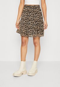 Svart kjol med lös passform, med ett abstrakt tryck i beige och brunt, plisserad design och elastisk midjeresår. Kombineras med kraftiga krämfärgade stövlar.