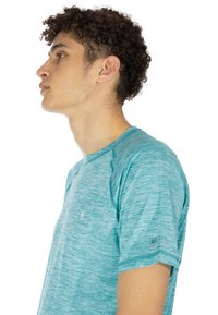 Turkos atletisk t-shirt med korta ärmar, texturerad tyg, raglan-seams och en liten logotyp på framsidan och ärmen.