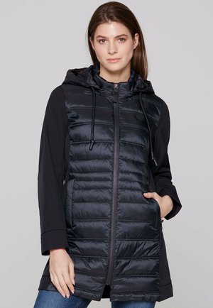 Black puffer vest with zip closure and drawstring hood, featuring a smooth, shiny texture and contrasting fabric panels on arms.