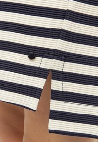 Tessuto di un abito a righe con colori blu navy e crema, caratterizzato da una trama a coste e un dettaglio in bottone nero sulla cucitura laterale.