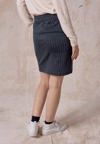 Dunkelblaue gestreifte Rock mit einem dehnbaren Bund, mittellanges Design, glatte Textur, getragen mit weißen High-Top-Sneakern.