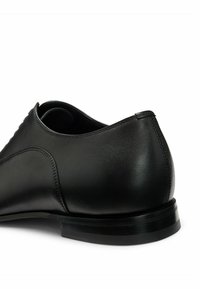 Black leather dress shoe, smooth texture, rounded toe, narrow heel, detailed stitching on the upper, minimalistic design, polished finish.