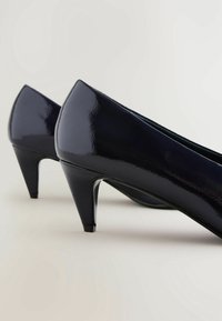 Escarpins en cuir verni noir avec un bout pointu et un talon aiguille élancé. Fini brillant, design épuré et texture lisse.