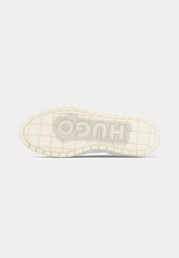 Biała gumowa podeszwa trampków z szachownicowym wzorem, z wytłoczonym logo "HUGO". Teksturowana powierzchnia z rowkami zapewniającymi przyczepność i elastyczność.