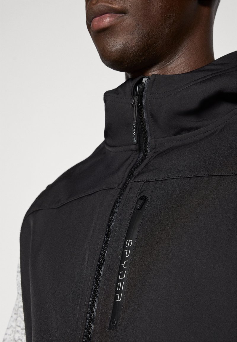 Veste noire avec un col montant, dotée d'une fermeture éclair sur le devant et d'une poche latérale. Le matériau est lisse avec une finition mate élégante.