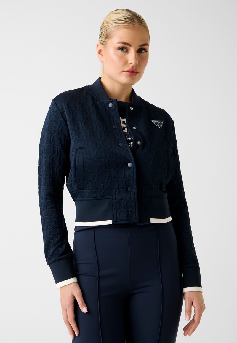 Marineblaue, kurze Bomberjacke mit strukturiertem Muster, gerippten Bündchen und weißen Akzenten. Sie verfügt über ein Logo auf der Brust und einen Druckknopfverschluss.