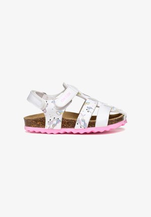 Sandalo bianco per bambini con stampa unicorno, suola rosa, sottopiede in sughero e cinturini regolabili in Velcro su sfondo bianco.