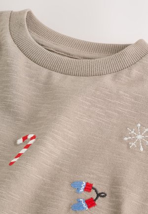 Sudadera de color beige claro con cuello acanalado, con bordados de bastón de caramelo, copo de nieve y mitones en azul, rojo y blanco.