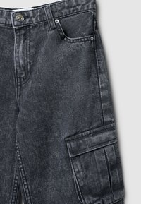 Pantaloni cargo in denim grigio scuro con finitura testurizzata, dotati di tasca frontale e tasca laterale, hardware in metallo e cuciture a contrasto.