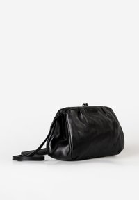 Borsa in pelle nera con superficie morbida e textured, dotata di chiusura a zip e lunga tracolla per il trasporto.