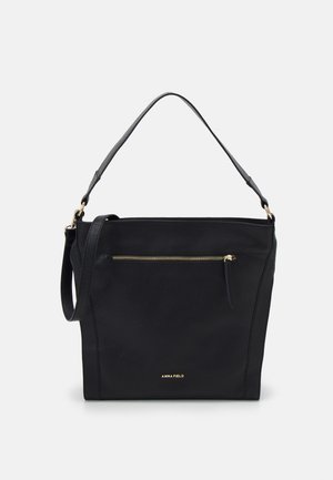 Schwarze Lederhandtasche mit einem Griff, vorderer Reißverschlusstasche, dezentem goldenen Logo "Anna Field" und minimalistischem Design auf neutralem Hintergrund.