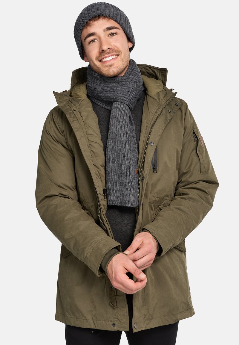 Olivenfarvet isoleret parka med hætte, med en frontlynlås, sidelommer samt en ribbet grå scarf og hat. Tekstureret stofdetalje synlig.