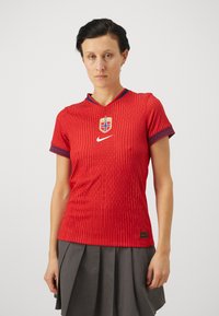 Red sports jersey with short sleeves, textured fabric, V-neck, featuring Norway national team logo and Nike swoosh, patterned cuffs, slim fit.