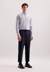 Hellblau kariertes Hemd mit Knöpfen und spitzem Kragen, kombiniert mit hoch taillierter marineblauer Hose und schwarzen Schuhen. Glatter Stoff und maßgeschneiderte Passform.