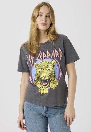 Camiseta gráfica gris con un diseño de leopardo amarillo con ojos azules, acentos morados y texto "Def Leppard" arriba. Manga corta y corte holgado.