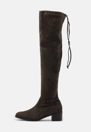 Bottes en daim vert olive montant jusqu'au genou, avec un bout pointu et un talon bloc moyen. Dotées d'un lien en haut pour un ajustement réglable.