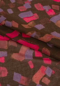 Tissu à motifs présentant des formes abstraites en rose, violet et rouille sur un fond brun. Texture douce, design lisse et couleurs vives.