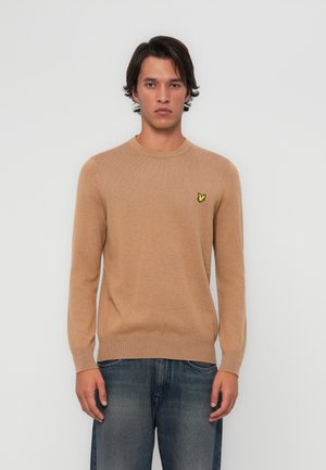 Pull en tricot beige avec un col rond et des manches longues. Présente un petit logo jaune sur la poitrine gauche. Fabriqué en tissu doux.