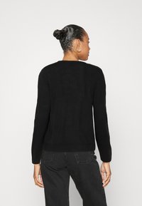 Pull noir avec un col ras du cou, des manches longues et des poignets et un ourlet côtelés. Texture douce, design minimaliste et silhouette ajustée.