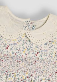 Blumenkleid mit einem weißen, bestickten Kragen. Der Hauptstoff ist leicht und hat ein Muster aus bunten Blumen sowie zarte Smockingdetails.